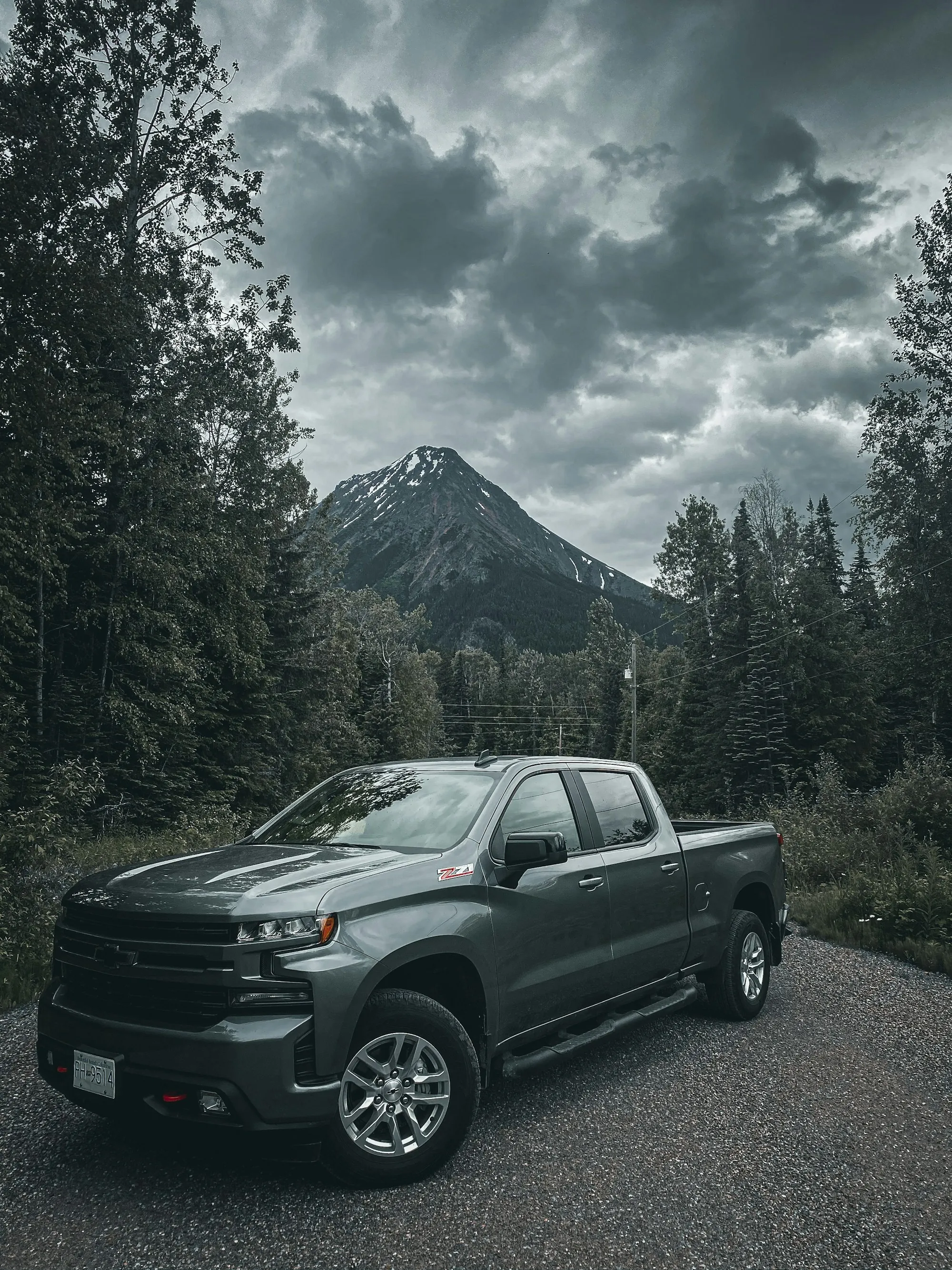 Grey diesel pickup parked beneath forested mountains
